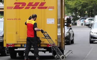 epa07572437 A parcel deliverer working for logistics company DHL works next to a DHL truck in Berlin, Germany, 15 May 2019. The coalition parties of the German Federal Government decided in a meeting of the coalition committee on 14 May 2019 to introduce a legal improvement in the social security of courier drivers. Logistics corporations should be obliged by law to guarantee the payment of social security contributions by employees of their subcontractors.  EPA/HAYOUNG JEON
