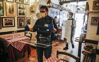 Giorgio Viscione (R) and his assistant, Nuova Gigaprint company, delivers some plexiglass separators to carry out a test of use in a typical Italian restaurant ''Il Ciak'',  at Trastevere district in Rome, Italy, 23 April 2020. Countries around the world are taking measures to stem the widespread of the SARS-CoV-2 coronavirus which causes the Covid-19 disease. ANSA / FABIO FRUSTACI