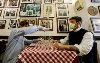 Giorgio Viscione (R), owner of Gigaprint, tests the plexiglass separators produced by his company with Valerio Calderonei, owner of a italian tipical restaurant 'Il Ciak'', at Trastevere district in Rome, Italy, 23 April 2020. Countries around the world are taking measures to stem the widespread of the SARS-CoV-2 coronavirus which causes the Covid-19 disease. ANSA / FABIO FRUSTACI