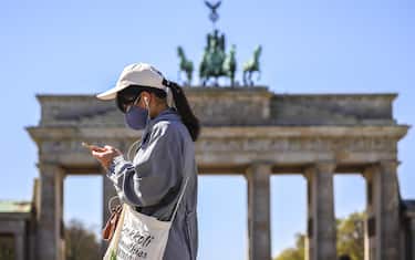 epa08373064 A visitor with a face mask in front of the Brandenburg Gate at Pariser Platz in Berlin, Germany, 20 April 2020. Several German Federal states issued requirements to wear mouth-nose masks in some scenarios on public places, among them Saxony, Mecklenburg- West Pomerania and Bavaria. Earlier in the day German Health Minister Jens Spahn delivered situation updates and informed about some loosening in the health restrictions. The German government and local authorities are beginning to consider to gradually end restrictions made to cope with the spread of the coronavirus SARS-CoV-2 which causes the COVID-19 disease.  EPA/OMER MESSINGER