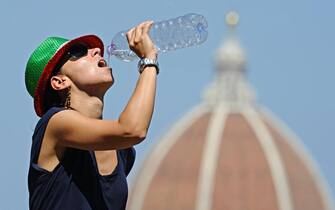 Una donna si rinfresca versandosi dell'acqua con una bottiglia a Firenze, 27  luglio 2013. ANSA/MAURIZIO DEGL' INNOCENTI 