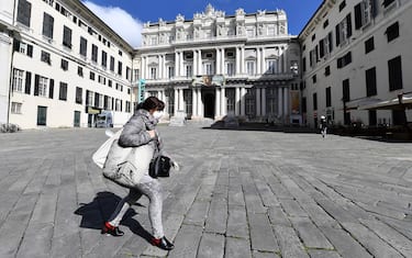 A woman wearing a protectve mask walks by in an almosto deserts Ducal Palace in  square in Genoa, Italy, 11 March 2020. Very few people walk around in the city center  for a quick shopping, other to take the dogs for a walk. In the historic center many stores voluntarily closed over the the extending of coronavirus quarantine measures  announced by Italian Prime Minister Giuseppe Conte in an attempt to stop the spreading of the novel coronavirus Covid-19.   ANSA/LUCA ZENNARO