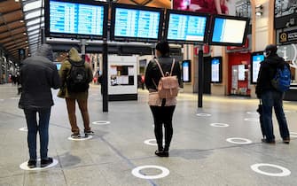 Passengers wearing protective facemasks stand within social distancing indicator circles as they wait for trains at Saint-Lazare Railway Station in Paris on May 11, 2020, on the first day of France's easing of lockdown measures in place for 55 days to curb the spread of the COVID-19 pandemic, caused by the new coronavirus. (Photo by BERTRAND GUAY / AFP)