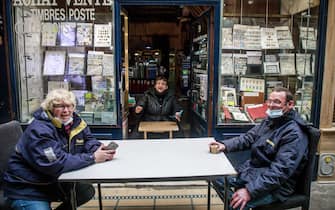 epa08414133 A stamp and post cards merchant (L) speaks with postal workers as she reopens her shop in Paris, France 11 May 2020. France begins a gradual easing of lockdow measures and restrictions although the coronavirus Covid-19 epidemic remains active.  EPA/CHRISTOPHE PETIT TESSON