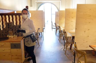 BOLZANO, ITALY - MAY 11: A waitress wearing a face mask at work while preparing the tables with wooden dividers in the restaurant on May 11, 2020 in Bolzano, Italy. The Bolzano province started the reopening of some businesses one week earlier than the rest of Italy, arising many controversies. (Photo by Alessio Coser/Getty Images)