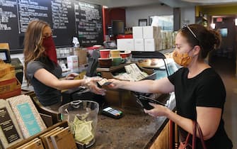 LAS VEGAS, NEVADA - MAY 09:  Store manager Erica Bond (L) rings up a drink order for Valerie Fogo of Nevada at Sambalatte in Boca Park Fashion Village as some businesses that were closed seven weeks ago to fight the spread of the coronavirus are allowed to reopen on May 9, 2020 in Las Vegas, Nevada. On Thursday, Nevada Gov. Steve Sisolak announced that under his Phase One reopening plan, the state would be allowing dine-in restaurants, hair and nail salons, some retail stores and other nonessential businesses to reopen today with strict social-distancing guidelines and occupancy restrictions in place. All employees who interact with the public are required to wear face coverings. Gaming establishments, including all hotel-casinos, are not reopening in Phase One.  (Photo by Ethan Miller/Getty Images)