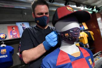 An employee places a mask with the logo of FC Barcelona on a mannequin at the FC Barcelona store on 25 May, 2020 in Barcelona. - Hundreds of Madrid residents flooded to the city's parks as lockdown measures were finally eased in the Spanish capital and in Barcelona, while beaches reopened in parts of the country after months-long closures. (Photo by LLUIS GENE / AFP) (Photo by LLUIS GENE/AFP via Getty Images)