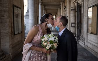 ROME, ITALY - APRIL 24: Sergio and Sophia kiss each other wearing protective masks after their wedding ceremony at Campidoglio, during the Coronavirus (COVID-19) pandemic, on April 24, 2020 in Rome, Italy. Italy is still remaining on lockdown until May 4th to stem the transmission of the Coronavirus (Covid-19). (Photo by Antonio Masiello/Getty Images)