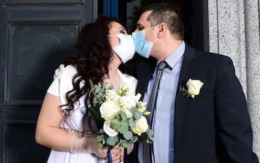 TOPSHOT - Newly-wed Italians Ester Concilio (L) and Rafaele Carbonelli kiss while wearing face masks following their wedding ceremony at the Briosco's town hall, about 45 km ( 28 miles) north of Milan, on May 11, 2020 during the country's lockdown aimed at curbing the spread of the COVID-19 infection, caused by the novel coronavirus. (Photo by Miguel MEDINA / AFP) (Photo by MIGUEL MEDINA/AFP via Getty Images)