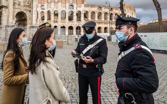 ROME, ITALY - DECEMBER 24: Carabinieri at the Colosseum checking two tourists during the first day of lockdown on Christmas Eve on December 24, 2020 in Rome, Italy. Italy will remain under a nationwide lockdown over the Christmas period, as authorities seek to avoid further spikes in coronavirus infections. Italy, currently in a second wave, is still one of Europe's worst hit countries with 1.98 million people infected with the virus. (Photo by Fabrizio Villa/Getty Images)