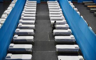 A worker arranges beds to prepare a quarantine centre in an indoor stadium at the Sarusajai Sports Complex during a government-imposed nationwide lockdown as a preventive measure against the COVID-19 coronavirus in Guwahati on March 29, 2020. (Photo by Biju BORO / AFP)