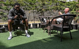 In this photo taken on April 11, 2020, Real Kashmir Football Club (RKFC) player Enyinnaya Loveday of Nigeria (L) and assistant coach Jimmy Lindsay of Scotland use their mobile phones at a restaurant hotel during a government-imposed nationwide lockdown as a preventive measure against the spread of the COVID-19 coronavirus in Srinagar. - Stranded by the coronavirus lockdown in one of the world's most militarised regions, Zambia's Aaron Katebe is one of 10 foreign footballers reduced to playing video games or training in a hotel gym in Indian-administered Kashmir. (Photo by Tauseef MUSTAFA / AFP) (Photo by TAUSEEF MUSTAFA/AFP via Getty Images)
