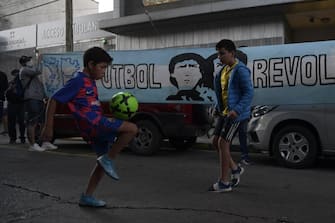 Kids play football near the entrance of the Hospital where Argentine former football star and coach of Gimnasia y Esgrima La Plata Diego Maradona, will undergo brain surgery for a blood clot, in Olivos, Buenos Aires province, on November 3, 2020. (Photo by JUAN MABROMATA / AFP) (Photo by JUAN MABROMATA/AFP via Getty Images)