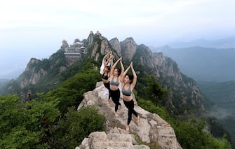 LUOYANG, CHINA - JUNE 20: People practice yoga on a cliff at an attitude of over 2,000 meters at Laojunshan mountain to welcome upcoming International Yoga Day on June 20, 2020 in Luoyang, Henan Province of China. (Photo by VCG/VCG via Getty Images)