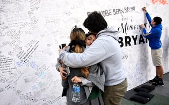 LOS ANGELES, CA - JANUARY 28: Bishop Amat High school students Alondra Arvizu, 17, (L) Lauren Griego (C) and Ian Butter, 18, hug after after leaving a condolence message on a board to pay their respects to Kobe Bryant and his daughter Gianna, 13, at a memorial set up outside of Staples Center on January 28, 2020 in Los Angeles, California. Kobe his daughter Gianna, 13, were among nine people killed in a helicopter crash on January 26 in Calabasas, California. (Photo by Kevork Djansezian/Getty Images)