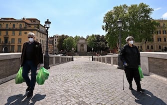TOPSHOT - People wearing a face mask carry their grocery across the Ponte Sisto bridge on April 24, 2020 in Rome, during the country's lockdown aimed at stopping the spread of the COVID-19 pandemic, caused by the novel coronavirus. (Photo by Alberto PIZZOLI / AFP) (Photo by ALBERTO PIZZOLI/AFP via Getty Images)