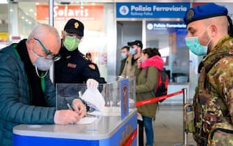 A soldier (R) and a police officer (Rear L) wearing a respiratory mask check a man filling an access form as part of control measures against the spread of the new COVID-19 coronavirus, at the Termini railway station in Rome on March 10, 2020. - Italy imposed unprecedented national restrictions on its 60 million people on March 10, 2020 to control the deadly coronavirus, as China signalled major progress in its own battle against the global epidemic. (Photo by Tiziana FABI / AFP) (Photo by TIZIANA FABI/AFP via Getty Images)