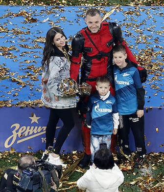 epa09174563 Zenit St. Petersburg's Artem Dzyuba (C) wearing a Deadpool costume is flanked by his family as he poses with the trophy after winning the Russian Premier League title following their match against Lokomotiv Moscow in St. Petersburg, Russia, 02 May 2021.  EPA/ANATOLY MALTSEV