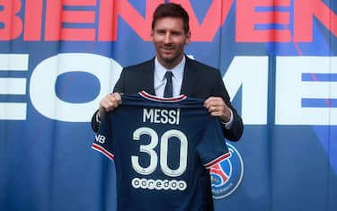 epa09409512 Argentinian striker Lionel Messi poses with his new PSG jersey after his press conference as part of his official presentation at the Parc des Princes stadium, in Paris, France, 11 August 2021. Messi arrived in Paris on 09 August and signed a contract with French soccer club Paris Saint-Germain.  EPA/CHRISTOPHE PETIT TESSON