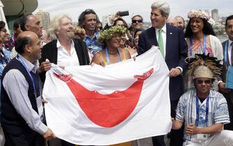 epa04964861 US Secretary of State John Kerry (3R) and British philanthropist Richard Branson (3L) hold a flag of Rapa Nui Island accompanied by indigenous from the island after the family photo after the inauguration of the Conference Our Ocean Chile 2015, in Valaparaiso, Chile, 05 October 2015.  EPA/FELIPE TRUEBA