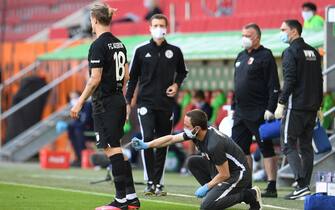 Augsburg's Croation defender Tin Jedvaj (L) receives medical attention  during the German first division Bundesliga football match FC Augsburg v VfL Wolfsburg on May 16, 2020 in Augsburg, southern Germany, as the season resumed following a two-month absence due to the novel coronavirus COVID-19 pandemic. (Photo by Tobias Hase / POOL / AFP) / DFL REGULATIONS PROHIBIT ANY USE OF PHOTOGRAPHS AS IMAGE SEQUENCES AND/OR QUASI-VIDEO (Photo by TOBIAS HASE/POOL/AFP via Getty Images)