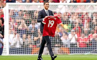 Manchester United's Raphael Varane holds up his shirt on the pitch as is is confirmed that he has signed for the club on a four-year deal ahead of the Premier League match at Old Trafford, Manchester. Picture date: Saturday August 14, 2021.