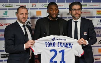 Olympique Lyonnais's newly recruited Cameroonian forward Karl Toko Ekambi (C) poses with his jersey next to Head of Lyon's recruitment unit Florian Maurice (L) and Olympique Lyonnais Brazilian sports director Juninho (R), during a press conference on January 21, 2020, at the Groupama Stadium in Decines-Charpieu near Lyon, central-eastern France. (Photo by PHILIPPE DESMAZES / AFP) (Photo by PHILIPPE DESMAZES/AFP via Getty Images)