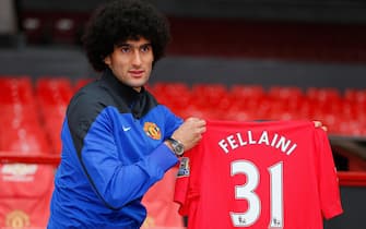 Manchester United's newly signed Belgian midfielder Marouane Fellaini poses with his shirt during a photo call at Old Trafford in Manchester, north-west England on September 13, 2013. Fellaini became Moyes first United signing for a fee of 27.5 million GBP (32.7 million Euros). AFP PHOTO/ANDREW YATES RESTRICTED TO EDITORIAL USE. No use with unauthorized audio, video, data, fixture lists, club/league logos or live services. Online in-match use limited to 45 images, no video emulation. No use in betting, games or single club/league/player publications. (Photo by Andrew YATES / AFP) (Photo by ANDREW YATES/AFP via Getty Images)