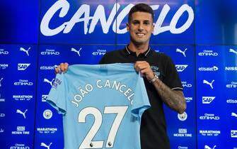 Manchester City's newly signed Portuguese defender Joao Cancelo poses with his club shirt during his unveiling at the City Football Academy in Manchester on August 8, 2019. (Photo by OLI SCARFF / AFP)        (Photo credit should read OLI SCARFF/AFP via Getty Images)