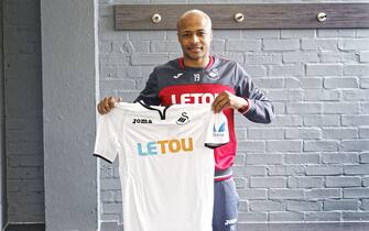 SWANSEA, WALES - FEBRUARY 01: Andre Ayew holds a team shirt as he is unveiled as a new Swansea City signing at The Fairwood Training Ground on February 01, 2018 in Swansea, Wales. (Photo by Athena Pictures/Getty Images)