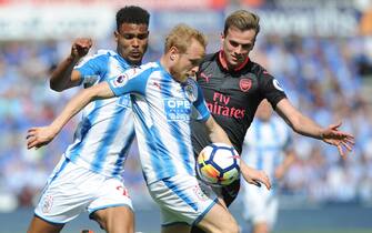 epa06733125 Arsenalâs Rob Holding (R) and Huddersfieldâs Alex Pritchard (C) and Huddersfieldâs Steve Mounie battle for the ball during the English Premier League soccer match between Huddersfield Town and Arsenal FC in Huddersfield, Britain, 13 May 2018.  EPA/RUI VIEIRA EDITORIAL USE ONLY. No use with unauthorised audio, video, data, fixture lists, club/league logos 'live' services. Online in-match use limited to 75 images, no video emulation. No use in betting, games or single club/league/player publications.