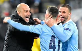 14 April 2021, North Rhine-Westphalia, Dortmund: Football: Champions League, knockout round, quarter-finals, second leg, Borussia Dortmund - Manchester City at Signal Iduna Park. Manchester's Phil Foden (M) celebrates with Manchester teammates Kyle Walker (r) and Manchester coach Josep "Pep" Guardiola (l) after scoring the 1:2 goal. Photo: Martin Meissner/AP-Pool/dpa