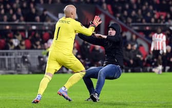 epa10486475 A pitch invader assaults Sevilla FC goalkeeper Marko Dmitrovic during the UEFA Europa league play-off soccer match between PSV Eindhoven and Sevilla FC, in Eindhoven, Netherlands, 23 February 2023.  EPA/OLAF KRAAK