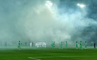 1236053596 AS Saint-Etienne and SCO Angers football players wait on the pitch after AS Saint-Etienne supporters launched smoke canisters to protest against the last place of their football club in the ranking of the French L1 championship, prior to the start of the French L1 football match between AS Saint-Etienne and SCO Angers at the Geoffroy Guichard stadium in Saint-Etienne, central France, on October 22, 2021. - Incidents broke out during the pre-match protocol Saint-Etienne/Angers of the 11th day of Ligue 1, caused by the ultras groups of the club stéphanois, and the kickoff of the game scheduled for 21:00 has been delayed. (Photo by PHILIPPE DESMAZES / AFP) (Photo by PHILIPPE DESMAZES/AFP via Getty Images)