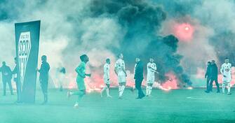 AS Saint-Etienne and SCO Angers football players react on the pitch after AS Saint-Etienne supporters launched smoke canisters to protest against the last place of their football club in the ranking of the French L1 championship, prior to the start of the French L1 football match between AS Saint-Etienne and SCO Angers at the Geoffroy Guichard stadium in Saint-Etienne, central France, on October 22, 2021. - Incidents broke out during the pre-match protocol Saint-Etienne/Angers of the 11th day of Ligue 1, caused by the ultras groups of the club stÃ©phanois, and the kickoff of the game scheduled for 21:00 has been delayed. (Photo by PHILIPPE DESMAZES / AFP) (Photo by PHILIPPE DESMAZES/AFP via Getty Images)