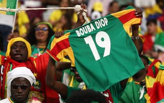 DOHA, QATAR - NOVEMBER 29: Fans of Senegal hold a shirt in tribute to Papa Bouba Diop during the FIFA World Cup Qatar 2022 Group A match between Ecuador and Senegal at Khalifa International Stadium on November 29, 2022 in Doha, Qatar. (Photo by James Williamson - AMA/Getty Images)