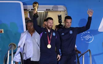 epa10374424 Lionel Messi (C) of the Argentina national soccer team descends a plane with the trophy of Qatar 2022 World Cup accompanied by head coach Lionel Scaloni (R), upon ther arrival to the International Airport of Ezeiza, some 22km of Buenos Aires, Argentina, 20 December 2022.  EPA/RAUL MARTINEZ