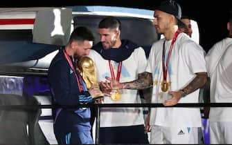 epa10374435 Lionel Messi of the Argentina national soccer team holds the trophy of Qatar 2022 World Cup next to Rodrigo De Paul (C) and Leandro Paredes upon ther arrival to International Airport of Ezeiza, some 22km of Buenos Aires, Argentina, 20 December 2022.  EPA/RAUL MARTINEZ