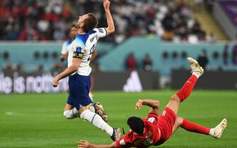 epa10318087 Harry Kane (L) of England is fouled by Morteza Pouraliganji (R) of Iran during the FIFA World Cup 2022 group B soccer match between England and Iran at Khalifa International Stadium in Doha, Qatar, 21 November 2022.  EPA/Neil Hall