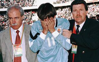 Uruguay's Josemir Lujambio covers his face as he leaves the playing field with Uruguayan team officials 20 July after Bolivia defeated Uruguay 1-0 in La Paz. Bolivia and Uruguay played in a France 98 World Cup qualification game. AFP PHOTO (Photo by STR / AFP) (Photo by STR/AFP via Getty Images)