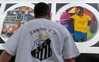 A fan of Santos football club looks at a mural by Brazilian artist Kobra depicting Brazilian retired football star Edson Arantes do Nascimento, known as Pele, in Santos, Sao Paulo state, Brazil on October 21, 2020. - The work, called 'Coracao Santista' (Santos' Heart), was finished days ahead of the 80th birthday of the football legend. Pele turns 80 on October 23, 2020. (Photo by Miguel SCHINCARIOL / AFP) / RESTRICTED TO EDITORIAL USE - MANDATORY MENTION OF THE ARTIST UPON PUBLICATION - TO ILLUSTRATE THE EVENT AS SPECIFIED IN THE CAPTION (Photo by MIGUEL SCHINCARIOL/AFP via Getty Images)