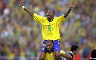 BRASILIA, BRAZIL:  Brazilian striker Robinho (above) is carried by forward Adriano celebrating Adriano's third goal -the fifth for Brazil- against Chile at the end of their FIFA's World Cup Germany 2006 qualifier match, 04 September 2005, at Mane Garrincha stadium in Brasilia. Brazil won 5-0 and qualified.  AFP PHOTO/ORLANDO KISSNER  (Photo credit should read ORLANDO KISSNER/AFP via Getty Images)