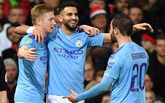 Manchester City's Algerian midfielder Riyad Mahrez (C) celebrates scoring his team's second goal with Manchester City's Belgian midfielder Kevin De Bruyne (L) and Manchester City's Portuguese midfielder Bernardo Silva during the English League Cup semi-final first leg football match between Manchester United and Manchester City at Old Trafford in Manchester, north west England on January 7, 2020. (Photo by Paul ELLIS / AFP) / RESTRICTED TO EDITORIAL USE. No use with unauthorized audio, video, data, fixture lists, club/league logos or 'live' services. Online in-match use limited to 75 images, no video emulation. No use in betting, games or single club/league/player publications. /  (Photo by PAUL ELLIS/AFP via Getty Images)