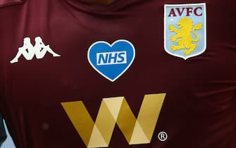 BIRMINGHAM, ENGLAND - JUNE 17: A detailed view of the NHS logo is seen on the front of an Aston Villa players shirt in support of the work they have been doing throughout the COVID-19 pandemic during the Premier League match between Aston Villa and Sheffield United at Villa Park on June 17, 2020 in Birmingham, United Kingdom. (Photo by Marc Atkins/Getty Images)