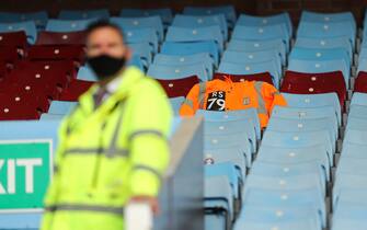 BIRMINGHAM, ENGLAND - JUNE 17: An orange stewards jacket is seen in the stands in memory of Dean Smith the head coach / manager of Aston Villas father Ron Smith, who passed away from Coronavirus as a steward wearing a face covering looks on prior to the Premier League match between Aston Villa and Sheffield United at Villa Park on June 17, 2020 in Birmingham, United Kingdom. (Photo by Matthew Ashton - AMA/Getty Images)