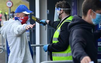 1228252444 Stewards wearing PPE (personal protective equipment) scan arriving supporters wearing face coverings ahead of the pre-season friendly football match between Brighton and Hove Albion and Chelsea at the American Express Community Stadium in Brighton, southern England on August 29, 2020. - The game is a 'pilot' event where a small number of fans will be present on a socially-distanced basis. The aim is to get fans back into stadiums in the Premier League by October. (Photo by Glyn KIRK / AFP) (Photo by GLYN KIRK/AFP via Getty Images)