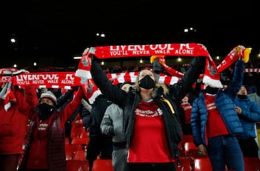 LIVERPOOL, ENGLAND - DECEMBER 06: Liverpool fans wearing face masks show their support by holding scarfs aloft whilst social distancing in the stand ahead of the Premier League match between Liverpool and Wolverhampton Wanderers at Anfield on December 06, 2020 in Liverpool, England. A limited number of fans (2000) are welcomed back to stadiums to watch elite football across England. This was following easing of restrictions on spectators in tiers one and two areas only. (Photo by Clive Brunskill/Getty Images)