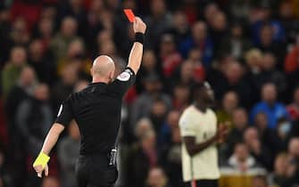English referee Anthony Taylor shows a red  card to Manchester United's French midfielder Paul Pogba (not pictured) during the English Premier League football match between Manchester United and Liverpool at Old Trafford in Manchester, north west England, on October 24, 2021. - RESTRICTED TO EDITORIAL USE. No use with unauthorized audio, video, data, fixture lists, club/league logos or 'live' services. Online in-match use limited to 120 images. An additional 40 images may be used in extra time. No video emulation. Social media in-match use limited to 120 images. An additional 40 images may be used in extra time. No use in betting publications, games or single club/league/player publications. (Photo by Oli SCARFF / AFP) / RESTRICTED TO EDITORIAL USE. No use with unauthorized audio, video, data, fixture lists, club/league logos or 'live' services. Online in-match use limited to 120 images. An additional 40 images may be used in extra time. No video emulation. Social media in-match use limited to 120 images. An additional 40 images may be used in extra time. No use in betting publications, games or single club/league/player publications. / RESTRICTED TO EDITORIAL USE. No use with unauthorized audio, video, data, fixture lists, club/league logos or 'live' services. Online in-match use limited to 120 images. An additional 40 images may be used in extra time. No video emulation. Social media in-match use limited to 120 images. An additional 40 images may be used in extra time. No use in betting publications, games or single club/league/player publications. (Photo by OLI SCARFF/AFP via Getty Images)