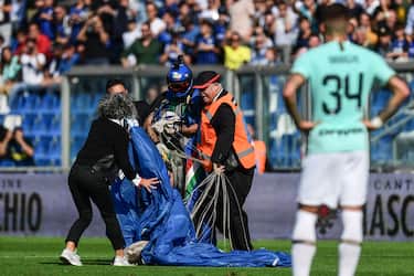 Inter Milan's Italian defender Cristiano Biraghi (R) looks on as security staffers evacuate a parachutist (Rear C-L with helmet) that unexpectedly landed on the pitch during the first half of the Italian Serie A football match Sassuolo vs Inter Milan on October 20, 2019 at the Mapei stadium in Reggio-Emilia. (Photo by Miguel MEDINA / AFP) (Photo by MIGUEL MEDINA/AFP via Getty Images)