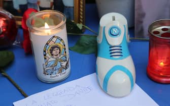 1229796314 A candle reading "Holy Diego" and a shoe with the logo of SSC Napoli football club are pictured by a small altar where people gather to mourn Argentinian football legend Diego Maradona on November 26, 2020 in the Spanish quarters of Naples, a day after the death of Maradona. - Maradona, widely remembered for his "Hand of God" goal against England in the 1986 World Cup quarter-finals, died on November 25, 2020 of a heart attack at his home near Buenos Aires in Argentina, while recovering from surgery to remove a blood clot on his brain. (Photo by Carlo Hermann / AFP) (Photo by CARLO HERMANN/AFP via Getty Images)